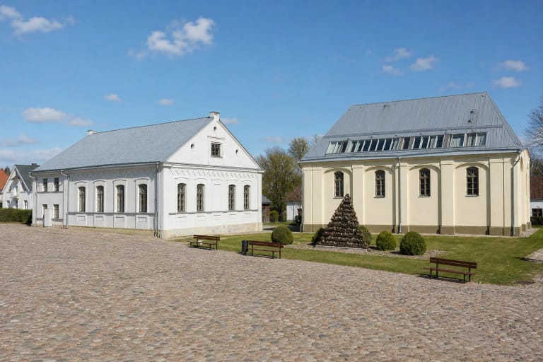 Akmenimis grįsta Kėdainių Senosios Rinkos aikštė ir dvi šviesių fasadų buvusios sinagogos