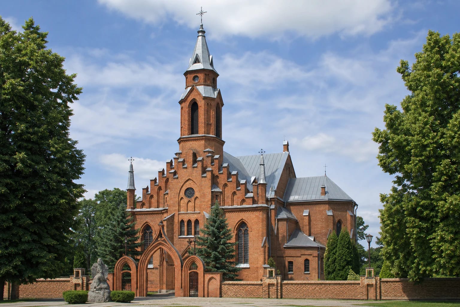 Kernavės Švč. Mergelės Marijos Škaplierinės bažnyčios vienabokštis raudonų plytų fasadas, neogotikiniai vartai ir medžiais apaugęs šventorius