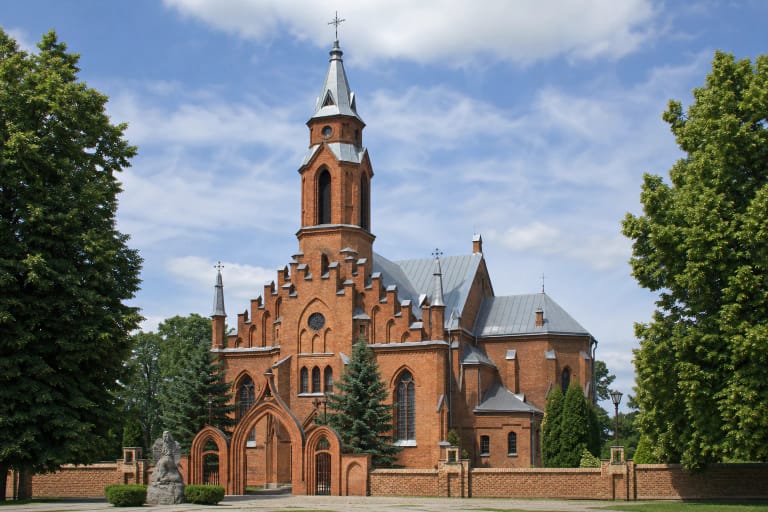 Kernavės Švč. Mergelės Marijos Škaplierinės bažnyčios vienabokštis raudonų plytų fasadas, neogotikiniai vartai ir medžiais apaugęs šventorius
