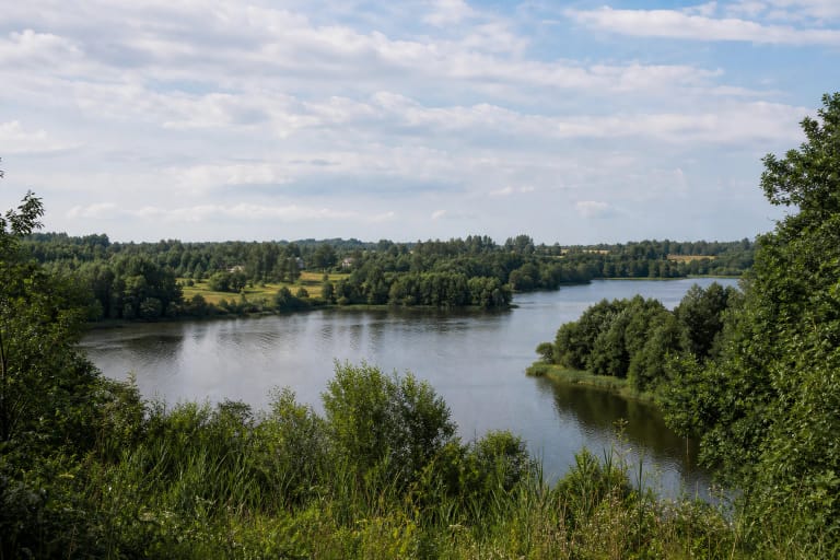 Kiemelių ežeras tarp medžiais apaugusių krantų, laukų ir Kiemelių apylinkių