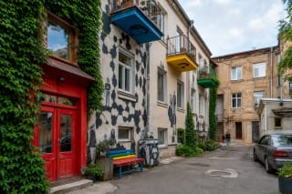 Kiemo galerijos Kaune gyvenamas kiemas su gebenėmis, raudonomis durimis, spalvotais balkonais ir portretais ant sienų