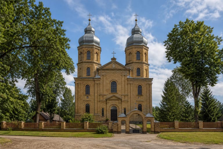 Gelsvų plytų Kietaviškių Švč. Trejybės bažnyčia su dviem barokiniais bokštų šalmais už arkinio šventoriaus vartų
