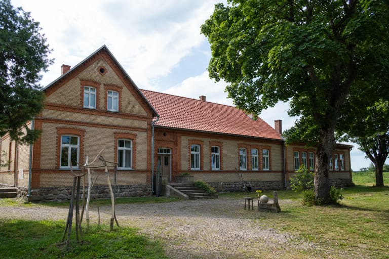 Kintų meno rezidencijos mūrinis pastatas ir kūrybinis kiemas vasaros dieną