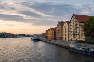 The Danė River waterfront in Klaipėda with small boats and restored half-timbered warehouses in evening light