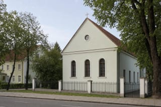 Santūrus šviesus Klaipėdos evangelikų baptistų bažnyčios fasadas su trimis aukštais arkiniais langais Vytauto gatvėje