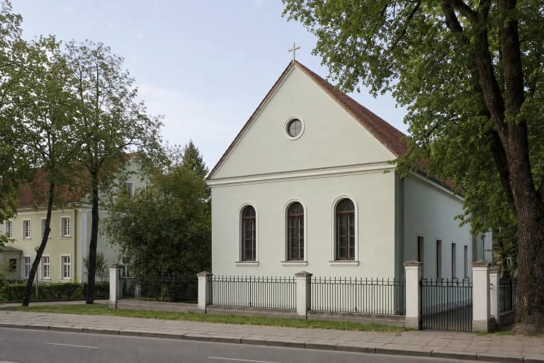 Santūrus šviesus Klaipėdos evangelikų baptistų bažnyčios fasadas su trimis aukštais arkiniais langais Vytauto gatvėje