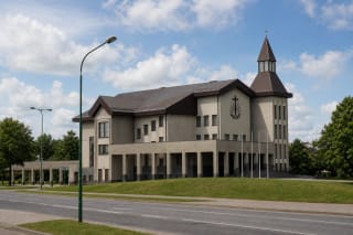 Moderni pilka Klaipėdos Naujoji apaštalų bažnyčia su tamsiais šlaitiniais stogais, aukštu bokštu ir dengta kolonada