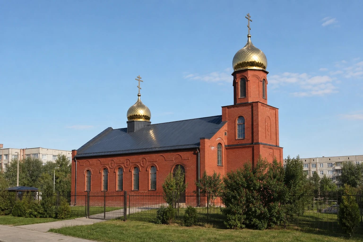 Краснокирпичная старообрядческая церковь Клайпеды с тёмной крышей, двумя золотыми куполами и крестами с тремя перекладинами