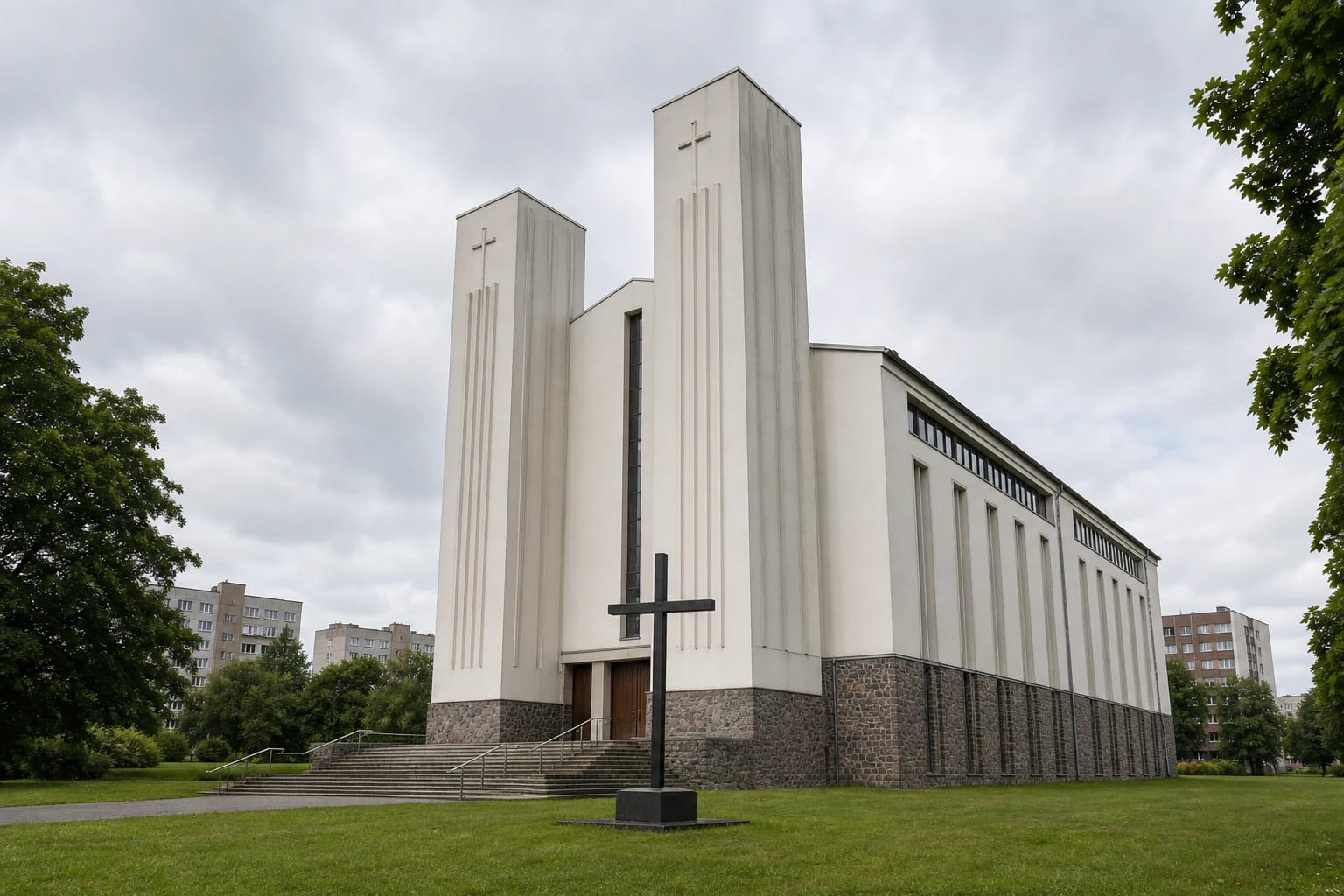 The white tapering towers, broad steps, and black lawn cross of Klaipėda Church of St Joseph the Worker