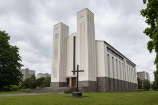 Белые сужающиеся башни церкви св. Иосифа Работника в Клайпеде, широкие ступени и чёрный крест на лугу
