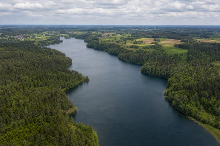 Aerial panorama of Klykių Lake with an indented wooded shoreline and village fields