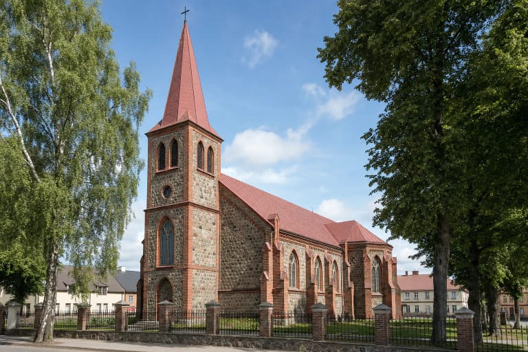 Kretingos evangelikų liuteronų bažnyčios akmens ir raudonų plytų fasadas su aukštu bokšto smaile
