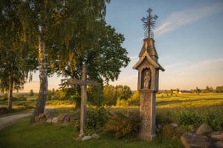 Lithuanian wooden roadside cross and koplytstulpis in a rural Lithuanian landscape