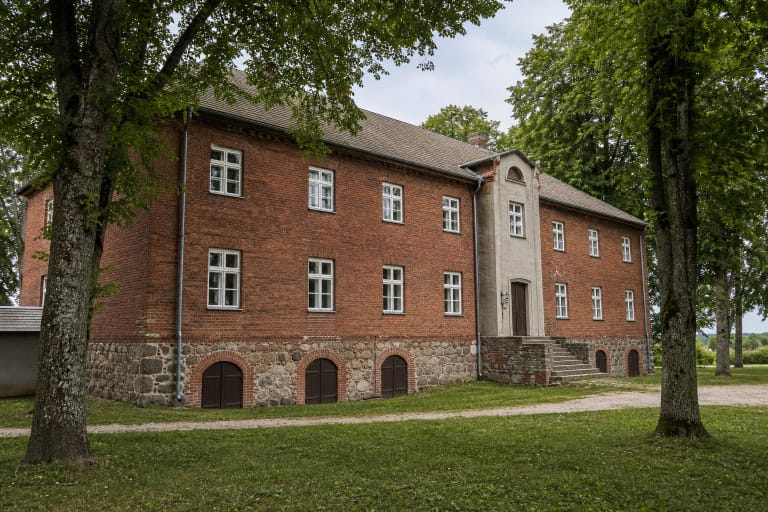 Kulių krašto muziejus raudonų plytų buvusios klebonijos pastate po brandžiais medžiais