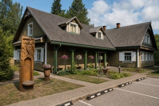 Labanoro regioninio parko lankytojų centro medinis pastatas su žaliu prieangiu, baltomis langinėmis ir miško tematikos medžio skulptūromis