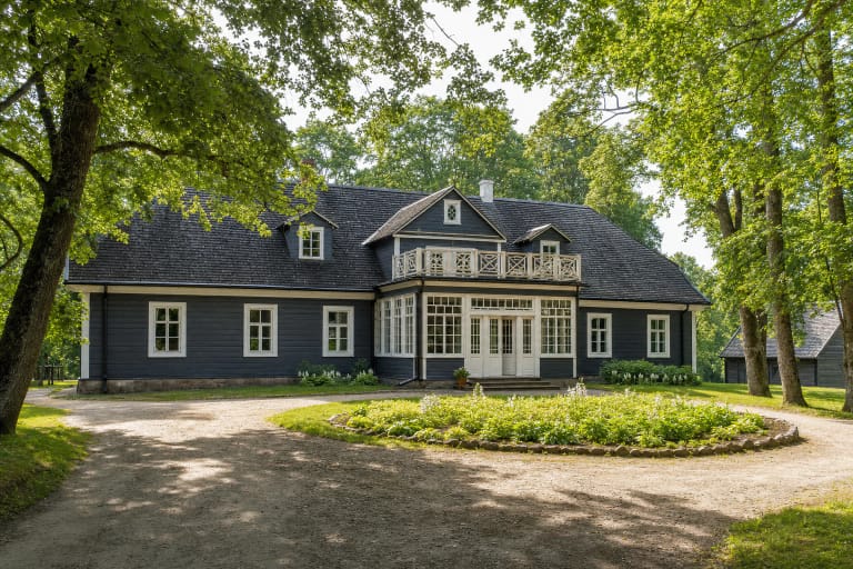Tamsiai dažytas medinis Paragių dvaro namas su baltais langais, centrine veranda ir balkonu žaliame parke