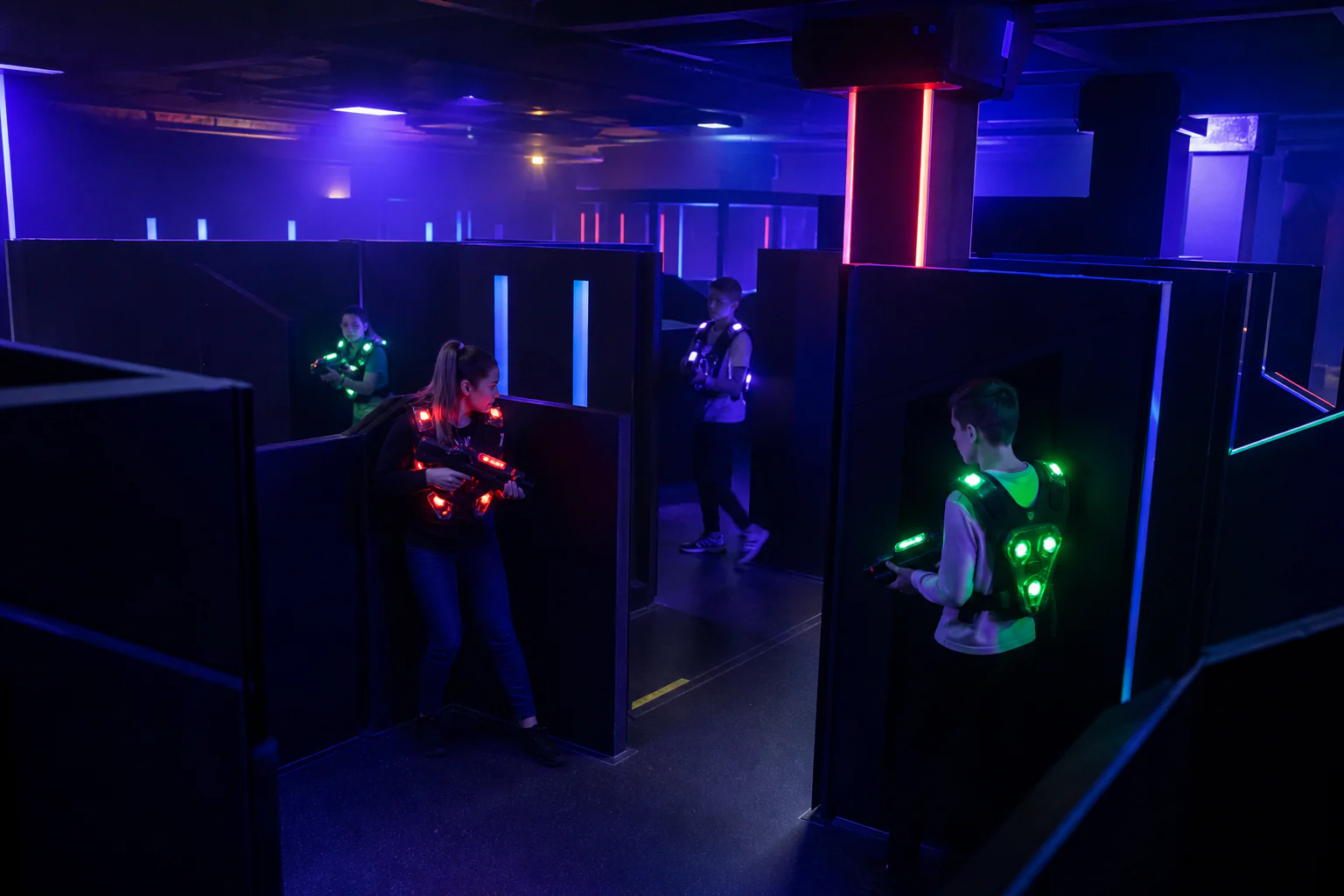 A dark Laser Arena maze with glowing player vests and compact laser-tag blasters