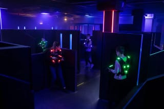 A dark Laser Arena maze with glowing player vests and compact laser-tag blasters