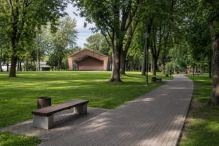 Окружённая деревьями дорожка парка Юозаса Лингиса в Шакяе с детской и велосипедной зонами отдыха