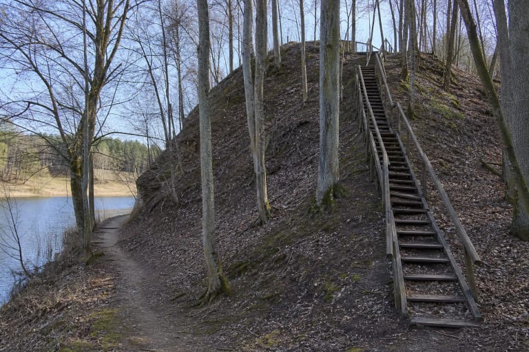 Steep wooded slopes and wooden steps at Lokėnėliai Hillfort beside the Lokys Reservoir