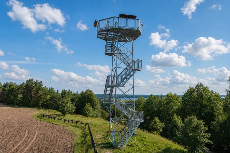 Lygumų apžvalgos bokšto atviri metaliniai laiptai ir daugiakampė aikštelė virš žalių Kretuono apylinkių