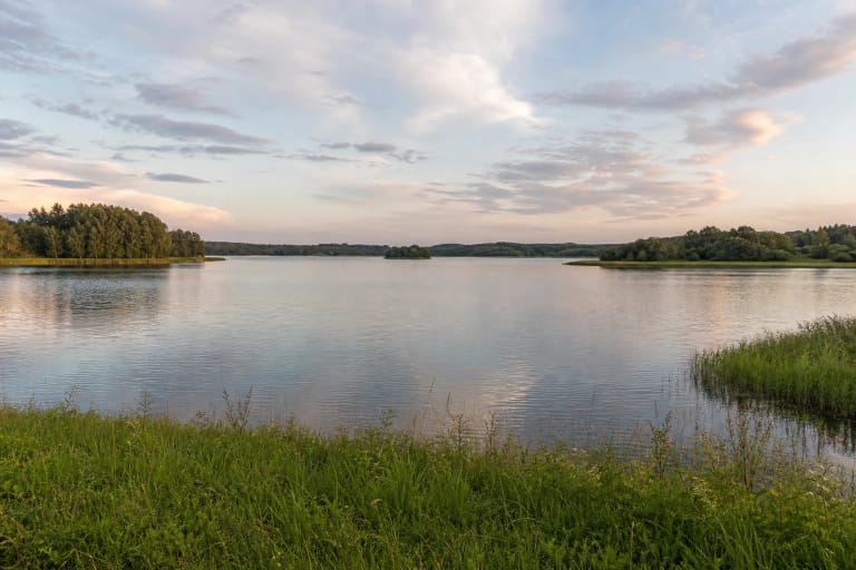 Broad Mastis Lake with a low wooded shore and a distant island