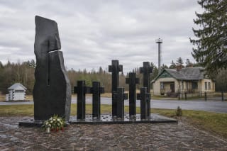 Чёрный гранитный мемориал трагедии в Мядининкае с семью крестами