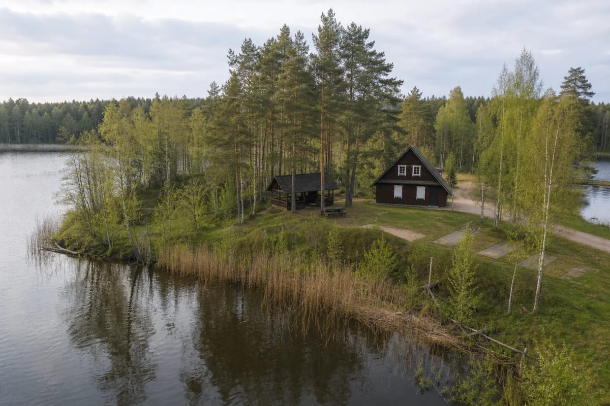 The isthmus between the Mergelės Akelės lakes, with the timber birdwatching centre, pine woods, and a quiet bank of the Stangė
