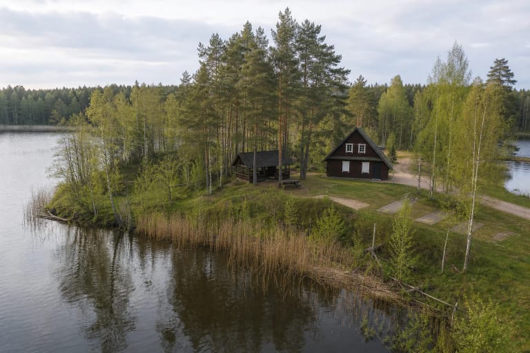 The isthmus between the Mergelės Akelės lakes, with the timber birdwatching centre, pine woods, and a quiet bank of the Stangė