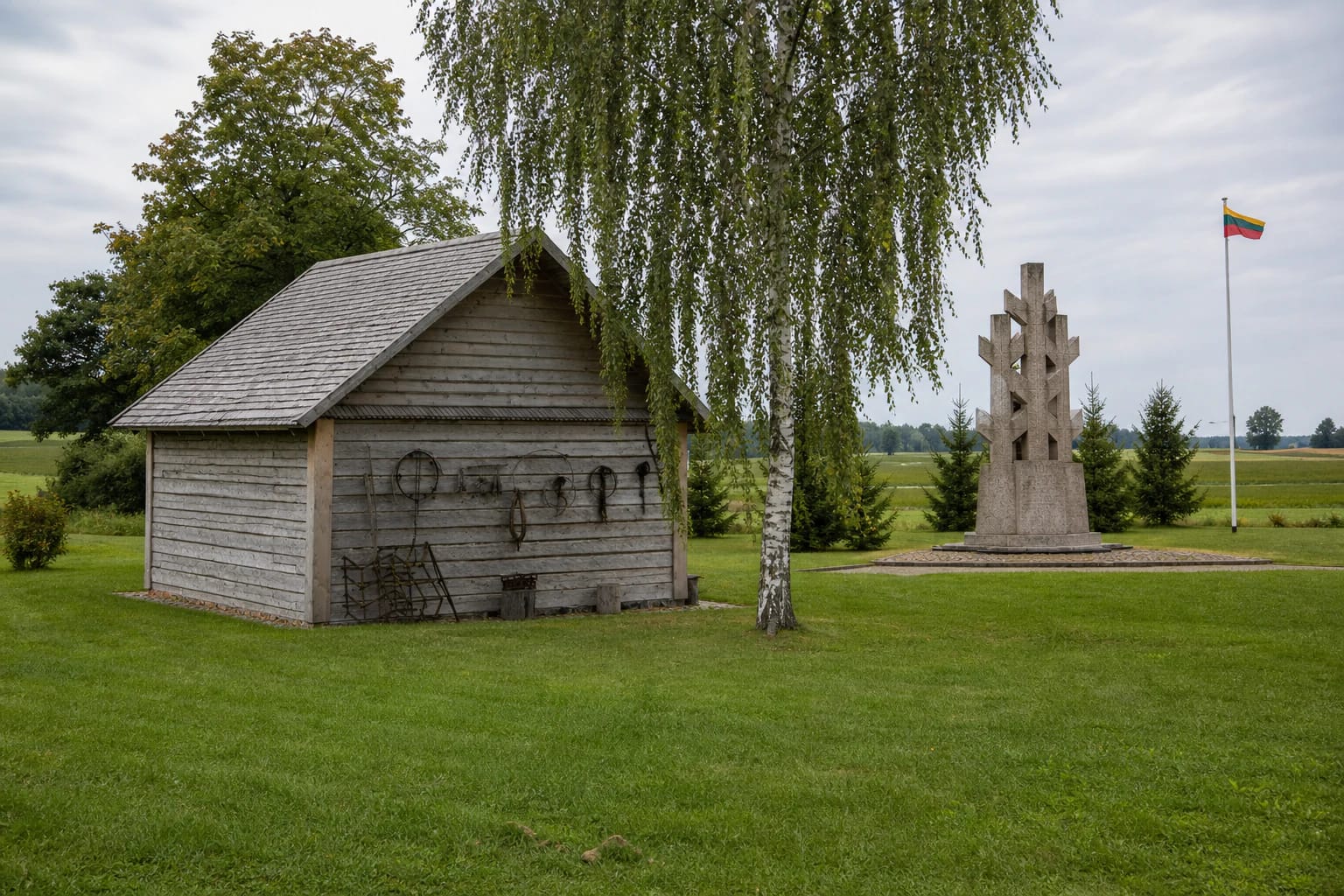 Atkurta pilka medinė klėtis virš Minaičių partizanų bunkerio ir LLKS deklaracijos memorialas kaimo sodybos kraštovaizdyje