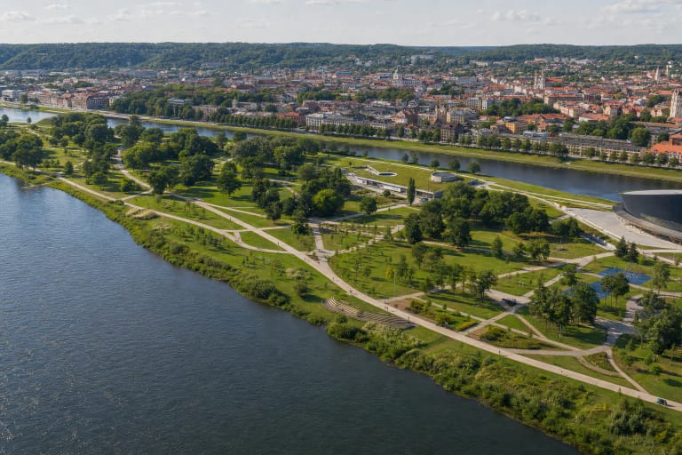 Nemunas Island Park in Kaunas with riverbanks, pale paths, sports courts, and the city skyline