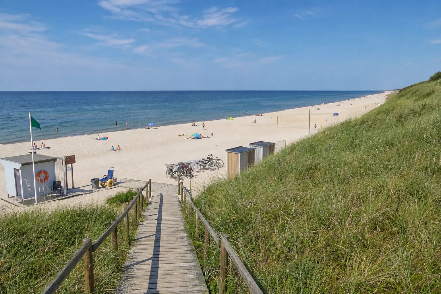 Wooden boardwalk crossing a grass-covered foredune to broad white-sand Nida Central Beach on the Baltic Sea