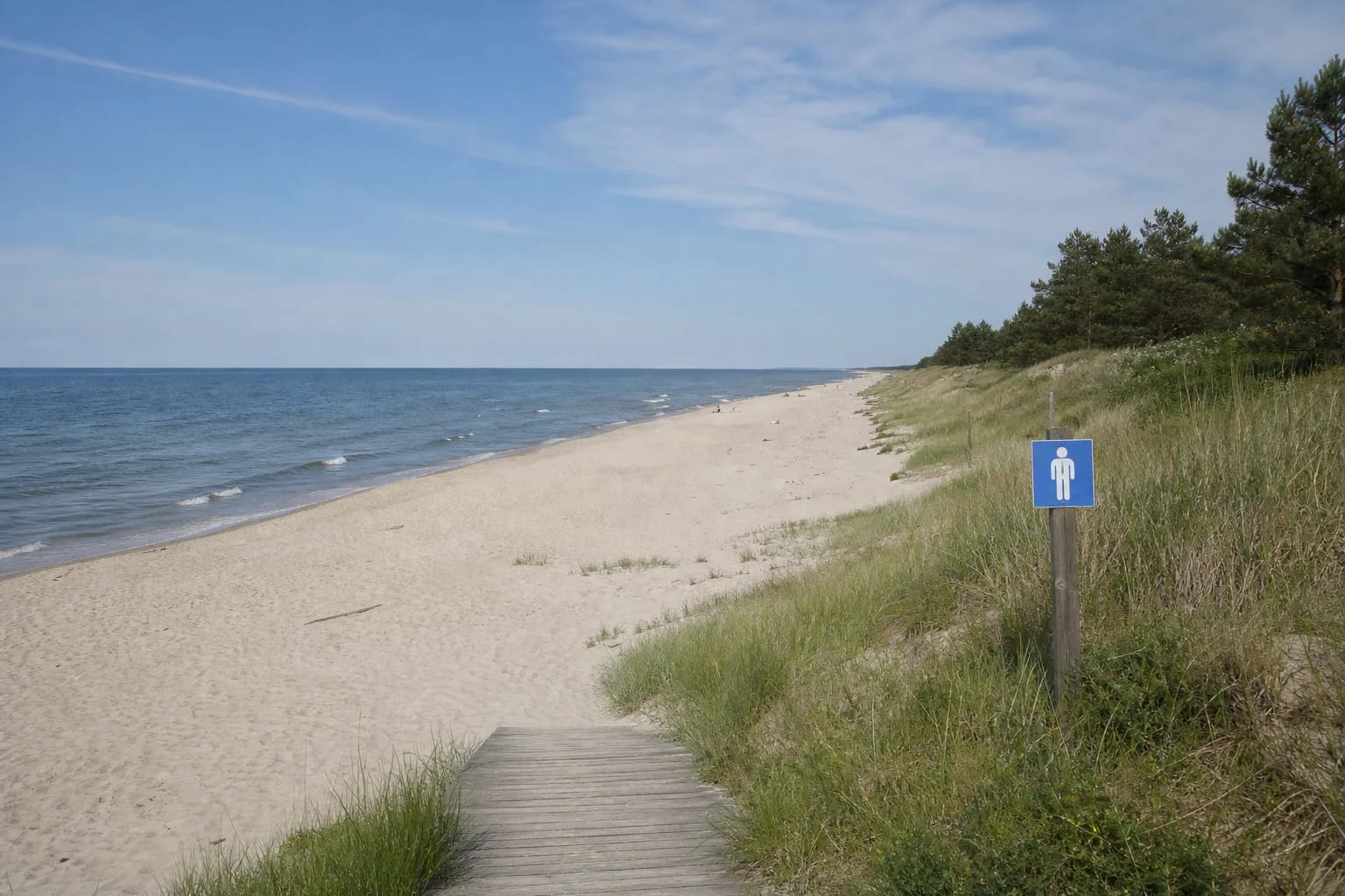A wooden access path leads to the quiet Nida Naturist Beach zone between the Baltic Sea and a grass-covered foredune