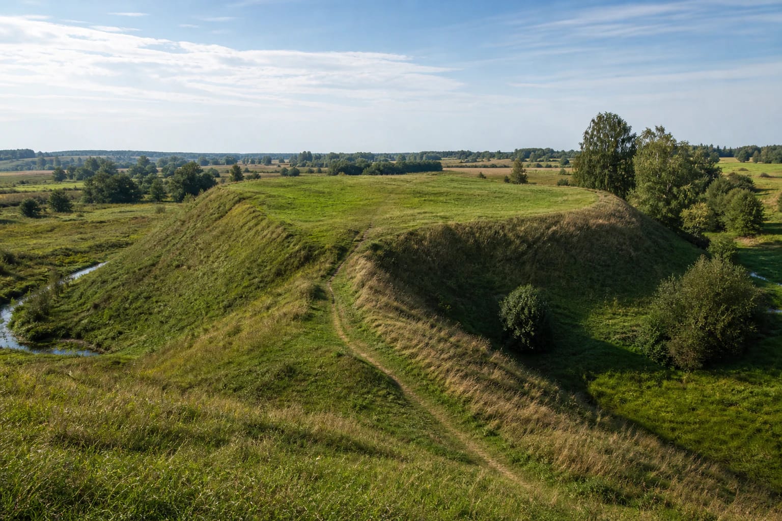 Grassy ramparts and broad platform of Pajevonys Hillfort in the fields of Suvalkija