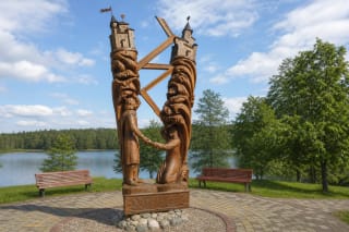 Две высокие дубовые фигуры Игнаса и Лины держатся за руки на берегу озера Папловинис в Игналине