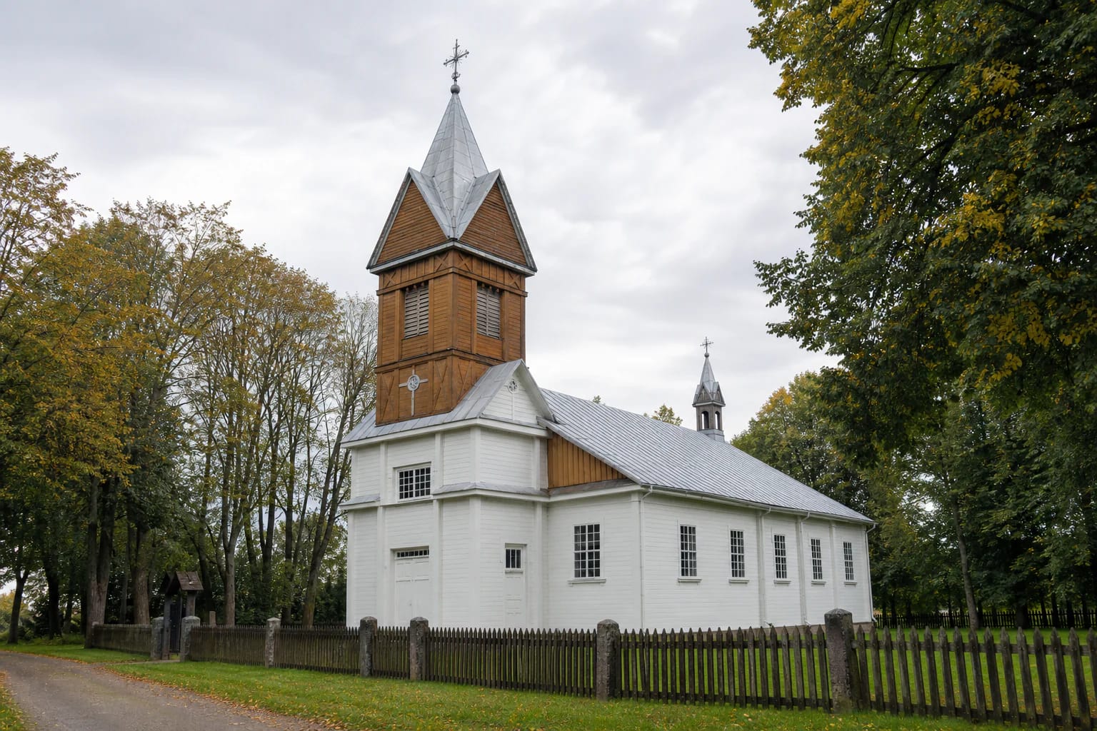 White wooden Paparčiai Church with a tall central tower and a smaller roof turret