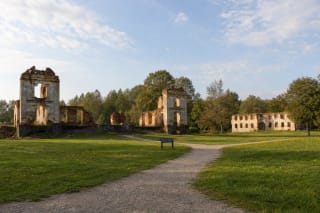 Plastered red-brick ruins of the Merkinė Manor palace of the Republic of Paulava standing in a green meadow beside the Merkys