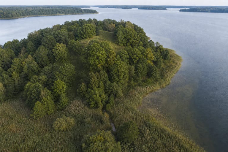 Mišku apaugęs Paveisininkų piliakalnio pusiasalis tarp Veisiejo ežero ir pelkėtos pakrantės