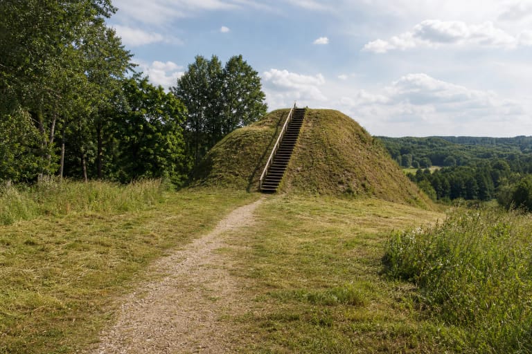 Grass-covered corner of Paverkniai Hillfort with timber stairs above the green Verknė valley