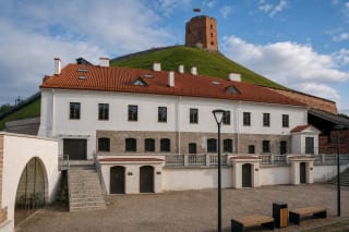 Restored white Castellan's House with a red-tiled roof below Gediminas Hill and its castle tower