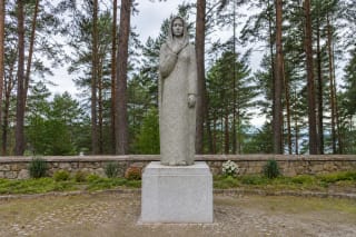 Granitinė Pirčiupių Motinos skulptūra žolėtoje memorialo aikštėje prie pušyno