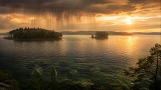 A water cloud spreads over Lake Plateliai and Castle Island as broad rain falls below