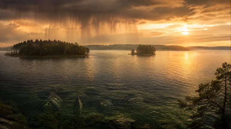 A water cloud spreads over Lake Plateliai and Castle Island as broad rain falls below