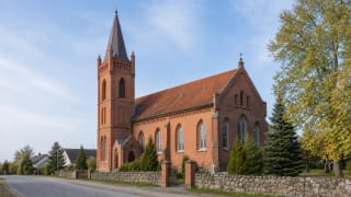 Plikiai Evangelical Lutheran Church with a red-brick facade and tower set to the left