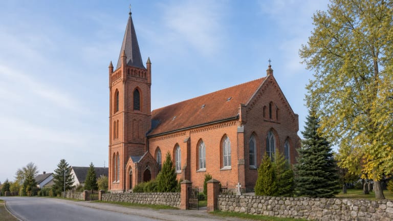 Plikiai Evangelical Lutheran Church with a red-brick facade and tower set to the left