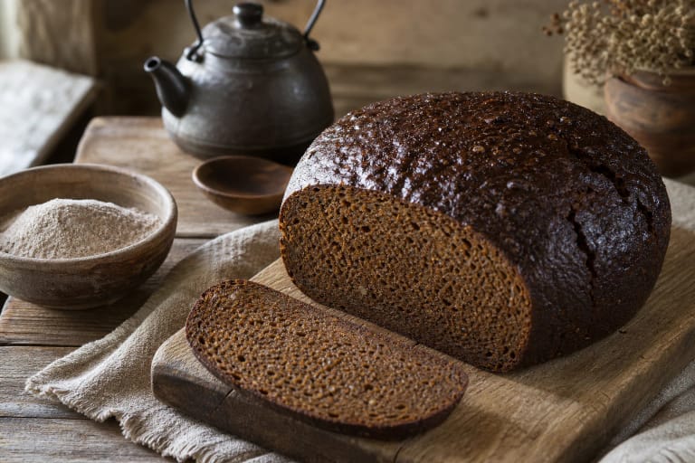 A loaf of scalded rye bread with a moist dark crumb, caraway, malt, and rye flour