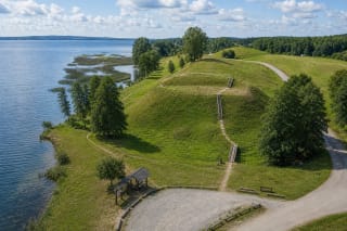 Зелёное городище Преломчишкес с деревянными ступенями на западном берегу синего озера Дусия