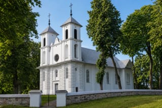 Белая церковь Пуни с двумя квадратными башнями, круглым витражом и каменной оградой церковного двора
