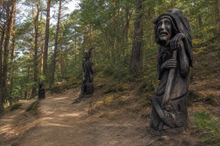 Raganų kalnas Juodkrantėje su medinėmis raganų ir velnių skulptūromis pušyno take