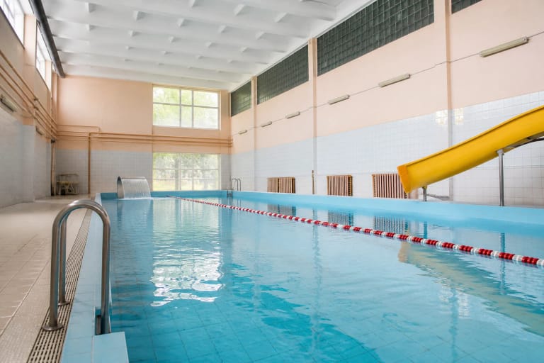 Rietavo baseino mėlynas vanduo, raudona takelio juosta ir geltona vandens čiuožykla